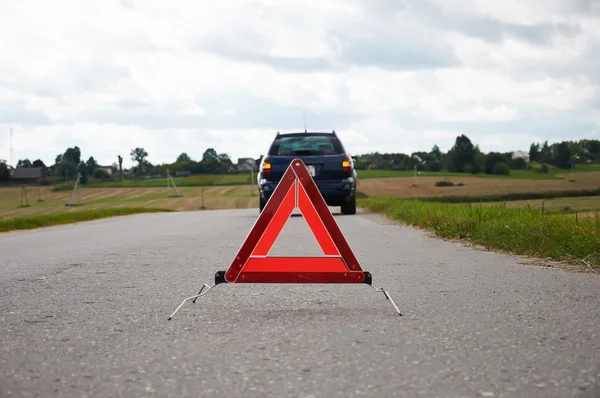 Red warning triangle with a broken down car Stock Picture