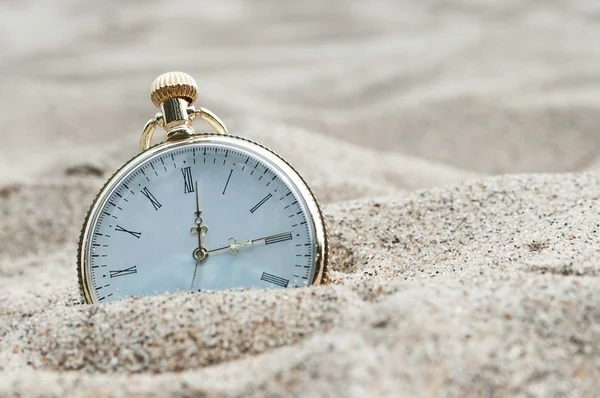 Pocket watch buried in sand Stock Photo