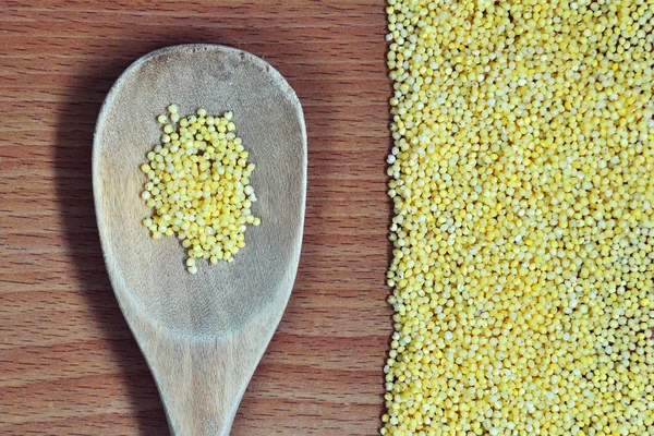 Splitted millet and spoon on the wooden background — Stock Photo, Image