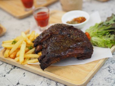 Domuz pirzolası, barbekü domuz pirzolası, patates kızartması sebze salatası, domates sosu, ahşap tepside temiz bir bardak, yiyecek.