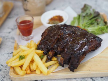 Domuz pirzolası, barbekü domuz pirzolası, patates kızartması sebze salatası, domates sosu, ahşap tepside temiz bir bardak, yiyecek.