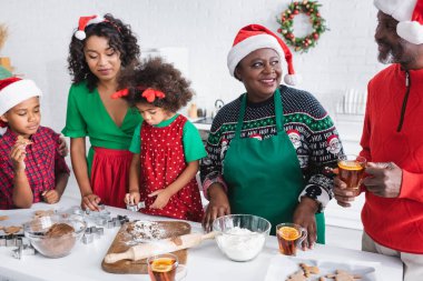 Afrika kökenli Amerikalı çocuklar, Noel Baba şapkalı anne ve büyükbabalarıyla Noel kurabiyesi hazırlıyorlar.