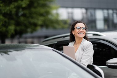 Arabasının otoparkına bakan neşeli Afro-Amerikalı iş kadını.