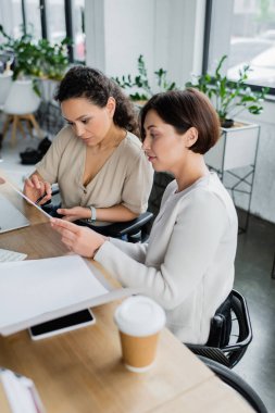 Afrikalı Amerikalı iş kadını ve fiziksel engelli meslektaşı ofiste birlikte çalışıyorlar.