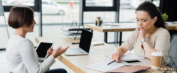 Mujer Negocios Positiva Señalando Con Mano Cerca Reflexivo Colega Afroamericano — Foto de Stock