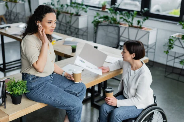 Mujer Negocios Silla Ruedas Mirando Infografías Cerca Colega Afroamericano Sentado — Foto de Stock