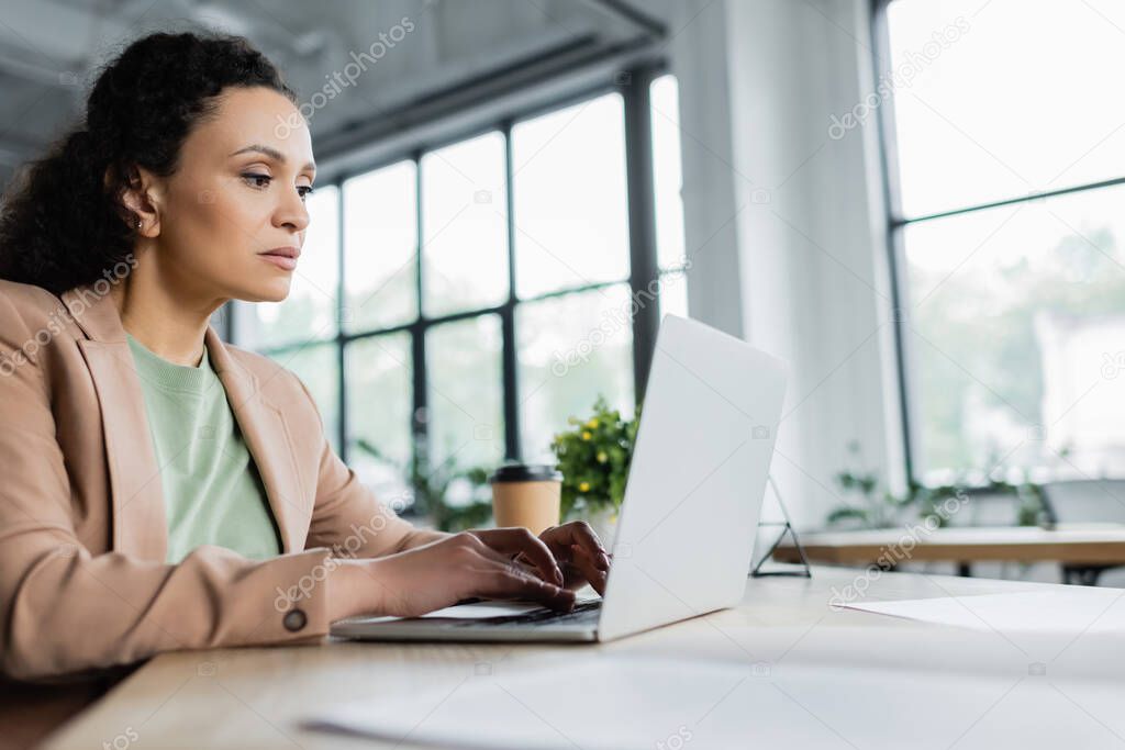 concentrated african american businesswoman typing on laptop in office