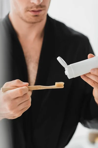 Vista Cortada Homem Desfocado Roupão Preto Segurando Escova Dentes Pasta — Fotografia de Stock