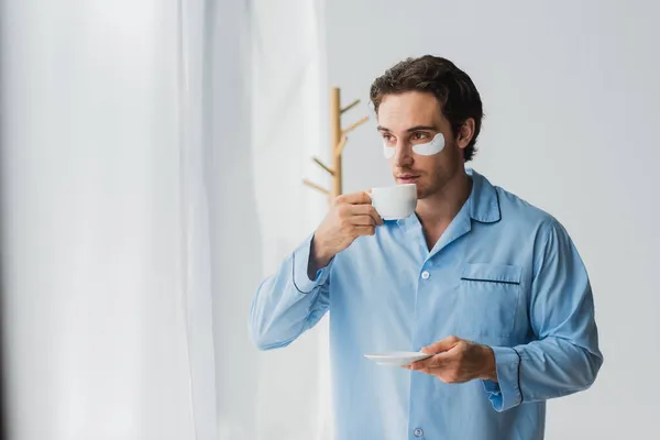 Ung Man Ögonlappar Och Pyjamas Håller Kopp Kaffe Hemma — Stockfoto