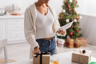 Afro-Amerikan kadının çay ve noel hediyelerinin yanında dijital tablet taşıdığı görüntüler. 