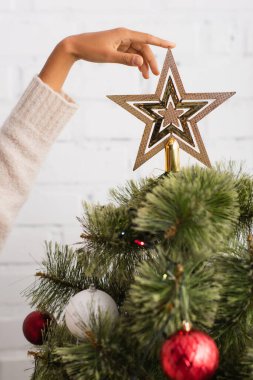Afrika kökenli Amerikalı bir kadının Noel ağacında yıldıza dokunuşunun görüntüsü. 