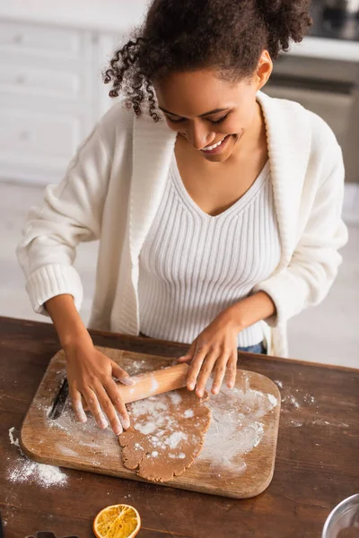 Uśmiechnięta Afroamerykanka Tocząca Ciasto Desce Krojenia Pobliżu Suchego Pomarańczowego Kawałka — Zdjęcie stockowe