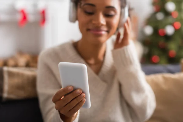 在家里过圣诞节时 戴着智能手机的模糊的非洲裔美国女人 — 图库照片