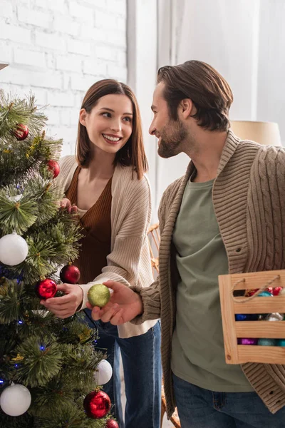 Freudiges Paar Lächelt Sich Beim Schmücken Des Weihnachtsbaums Hause — Stockfoto