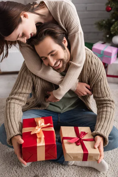 Mulher Sorridente Abraçando Marido Feliz Sentado Chão Com Presentes Natal — Fotografia de Stock