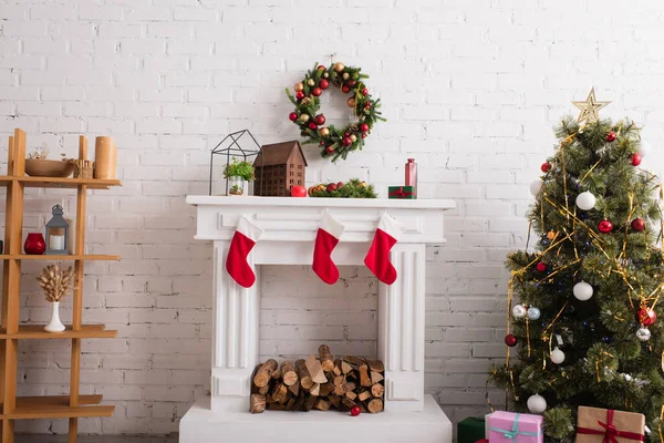 装飾された松の木とリビングルームの木のラックの近くのクリスマスストッキングと暖炉 — ストック写真