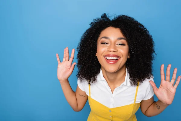 Wesoła Afroamerykanka Uśmiecha Się Kamery Macha Dłońmi Odizolowanymi Niebiesko — Zdjęcie stockowe
