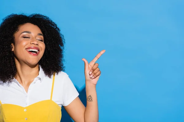 Cheerful African American Woman Closed Eyes Pointing Finger Blue — Stock Photo, Image