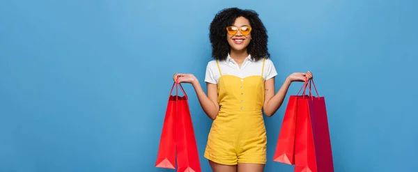 Vrolijk Afrikaans Amerikaanse Vrouw Gele Jumpsuit Bril Staan Met Boodschappentassen — Stockfoto