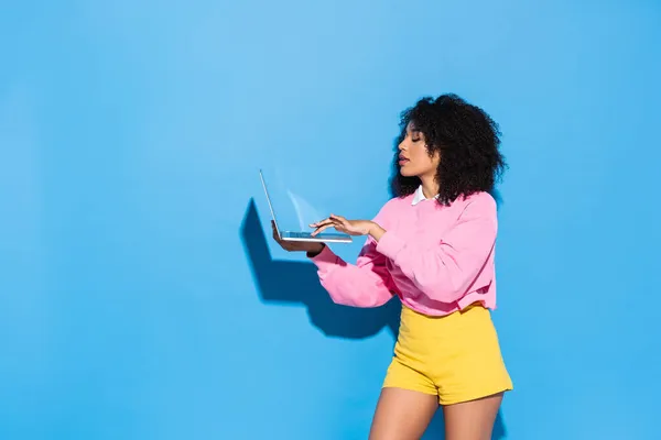 Fiatal Afro Amerikai Sárga Rövidnadrágban Rózsaszín Pulóver Segítségével Laptop Kék — Stock Fotó