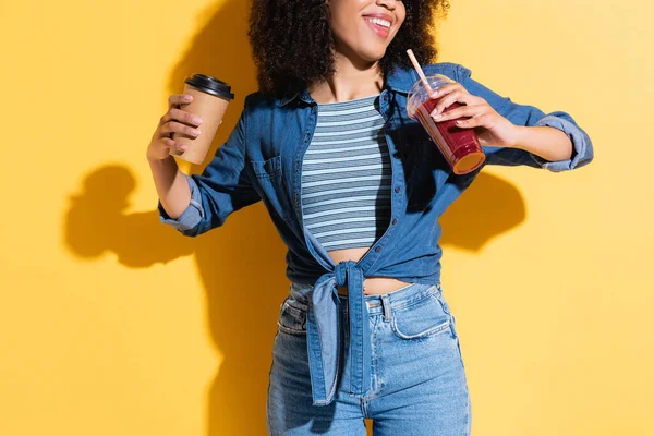 Częściowy Widok Uśmiechniętej Afroamerykanki Trzymającej Kawę Wynos Smoothie Yellow — Zdjęcie stockowe