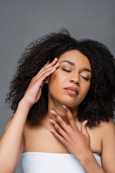 young african american woman with perfect skin touching neck and face isolated on grey