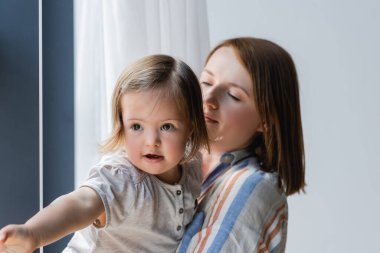 Blurred mother looking at daughter with down syndrome at home  clipart