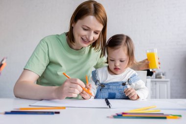 Mutfakta Down sendromlu gülümseyen anne ve kız çizimleri. 