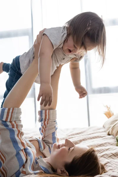 Madre Sorridente Che Solleva Bambino Con Sindrome Sul Letto — Foto Stock