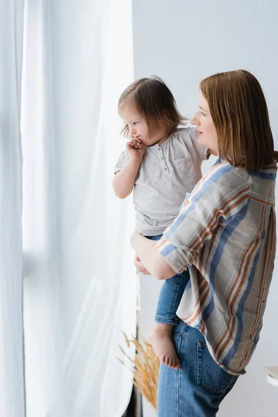 Mulher Segurando Filha Com Síndrome Perto Cortinas Casa — Fotografia de Stock