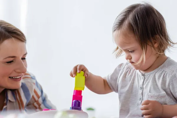 Barn Med Downs Syndrom Som Leker Byggeklosser Nærheten Mor Hjemme – stockfoto