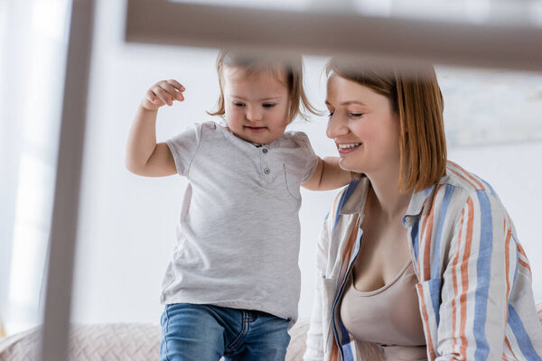 Smiling mom near daughter with down syndrome at home 