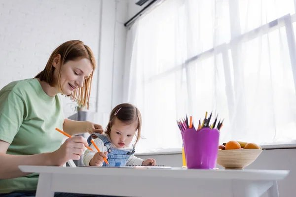 父母和小孩在厨房里画着接近彩色铅笔和水果的唐氏综合征 — 图库照片