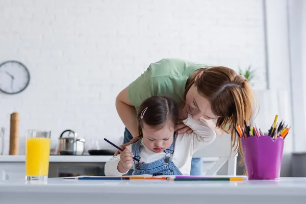笑顔女性巨大娘とともにダウン症候群保持色鉛筆でキッチン — ストック写真