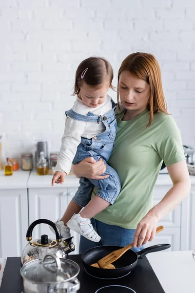 Kvinna Hålla Dotter Med Ner Syndrom Medan Matlagning Köket — Stockfoto