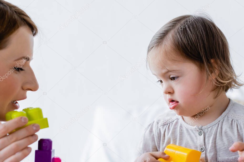 Parent and kid with down syndrome playing building blocks at home 