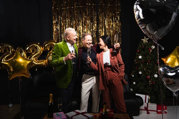 Positivi Amici Multietnici Con Champagne Vicino Palloncini Albero Natale Sfondo — Foto Stock