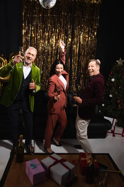 Positivo Amici Multietnici Con Champagne Ballando Vicino Regali Albero Natale — Foto Stock