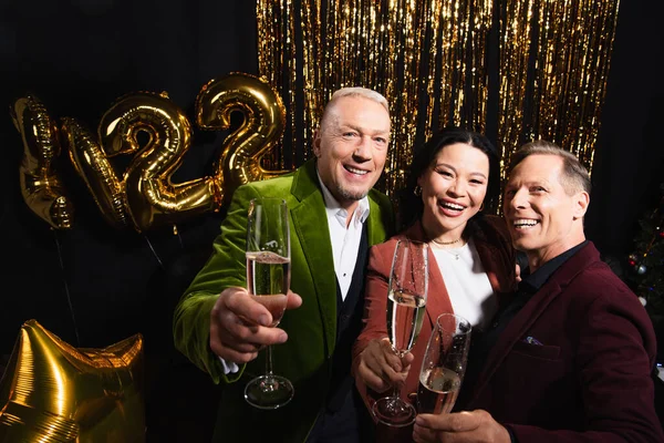 Sonrientes Amigos Multiétnicos Sosteniendo Champán Cerca Globos Oropel Sobre Fondo — Foto de Stock