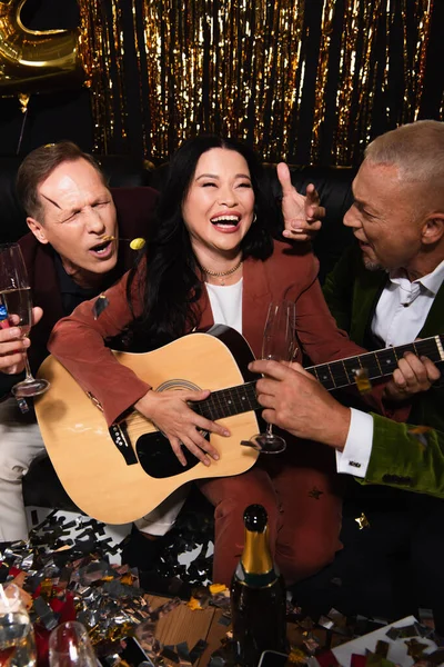 Smiling Asian Woman Playing Acoustic Guitar Friends Champagne Confetti Black — Stock Photo, Image