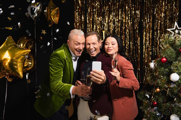 Leende Multietniska Vänner Med Champagne Tar Selfie Smartphone Nära Julgran — Stockfoto