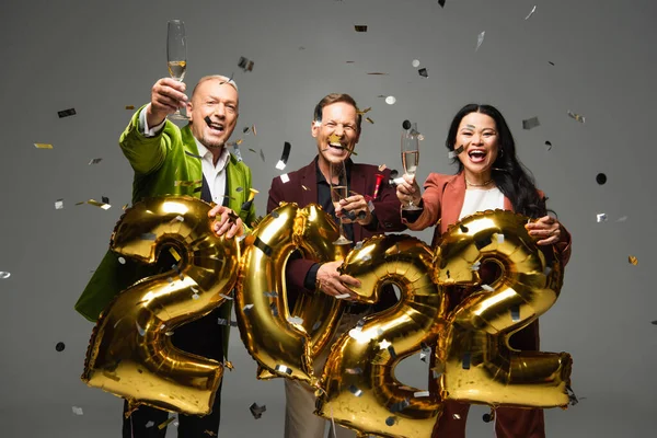 Felices Amigos Multiétnicos Sosteniendo Champán Mirando Cámara Cerca Globos Forma — Foto de Stock