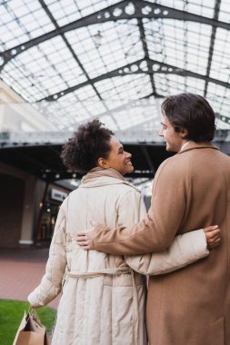 Alışveriş merkezinde birbirlerine bakarken gülümseyen mutlu bir çift.