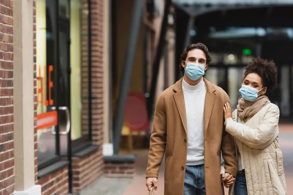 Jovem Casal Multiétnico Máscaras Médicas Mãos Dadas Enquanto Caminhava Shopping — Fotografia de Stock