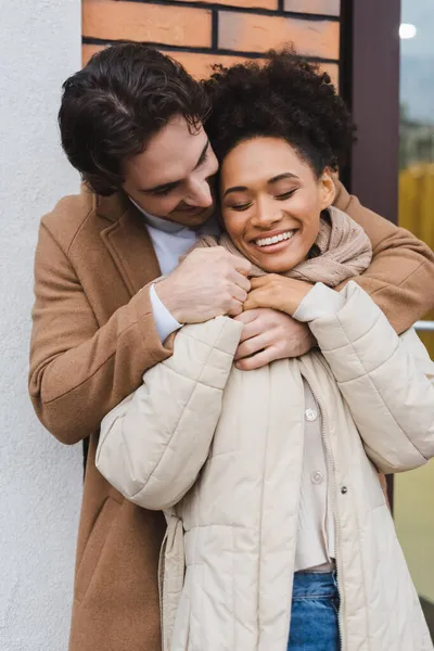 快乐的男人在室外大楼附近拥抱快乐的非洲女友 — 图库照片