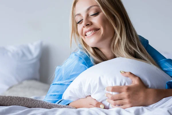快乐的金发女人躺在卧室的枕头上 — 图库照片