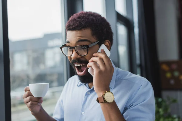Spännande Afrikansk Amerikansk Affärsman Talar Smartphone Och Hålla Kopp Kontoret — Stockfoto