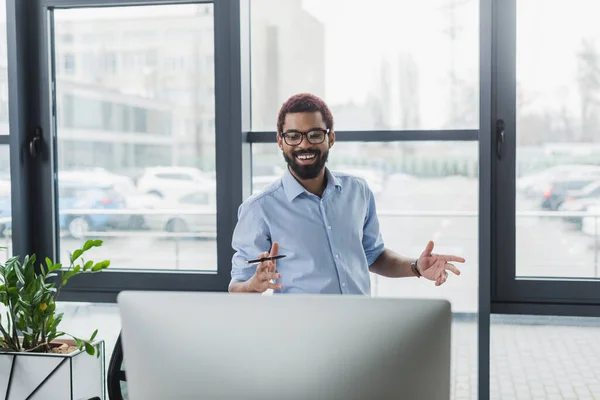 幸せなアフリカ系アメリカ人ビジネスマンとペンオフィスのコンピュータモニターを見て — ストック写真