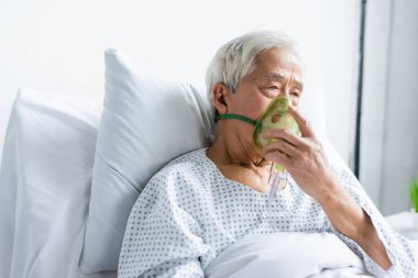 Hastanede yatarken oksijen maskesi takan kıdemli Asyalı hasta. 