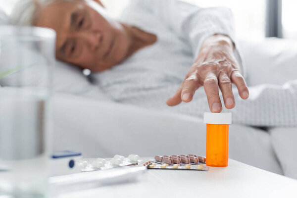 Blurred asian patient taking pills near water in hospital ward 